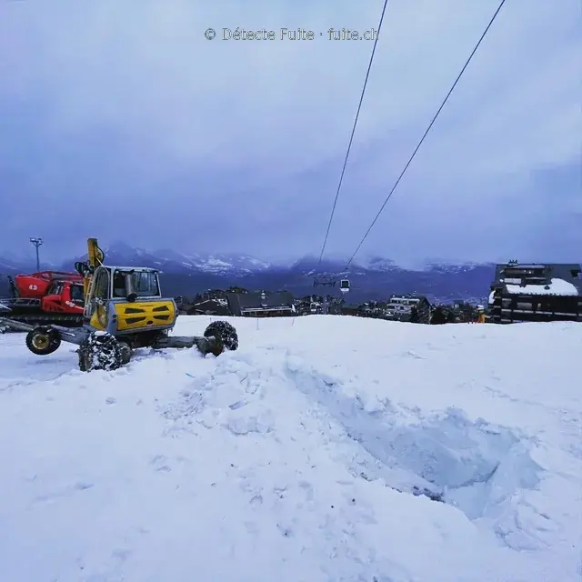 Engin de chantier et canon à neige sur un domaine skiable en hiver